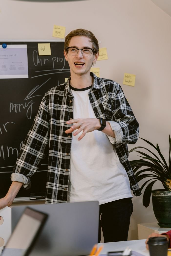 Man in plaid shirt presenting in a casual office environment.