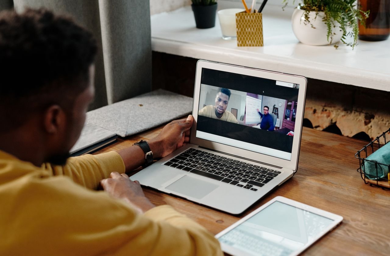 A man participates in an online video conference call from home using his laptop, fostering remote communication.